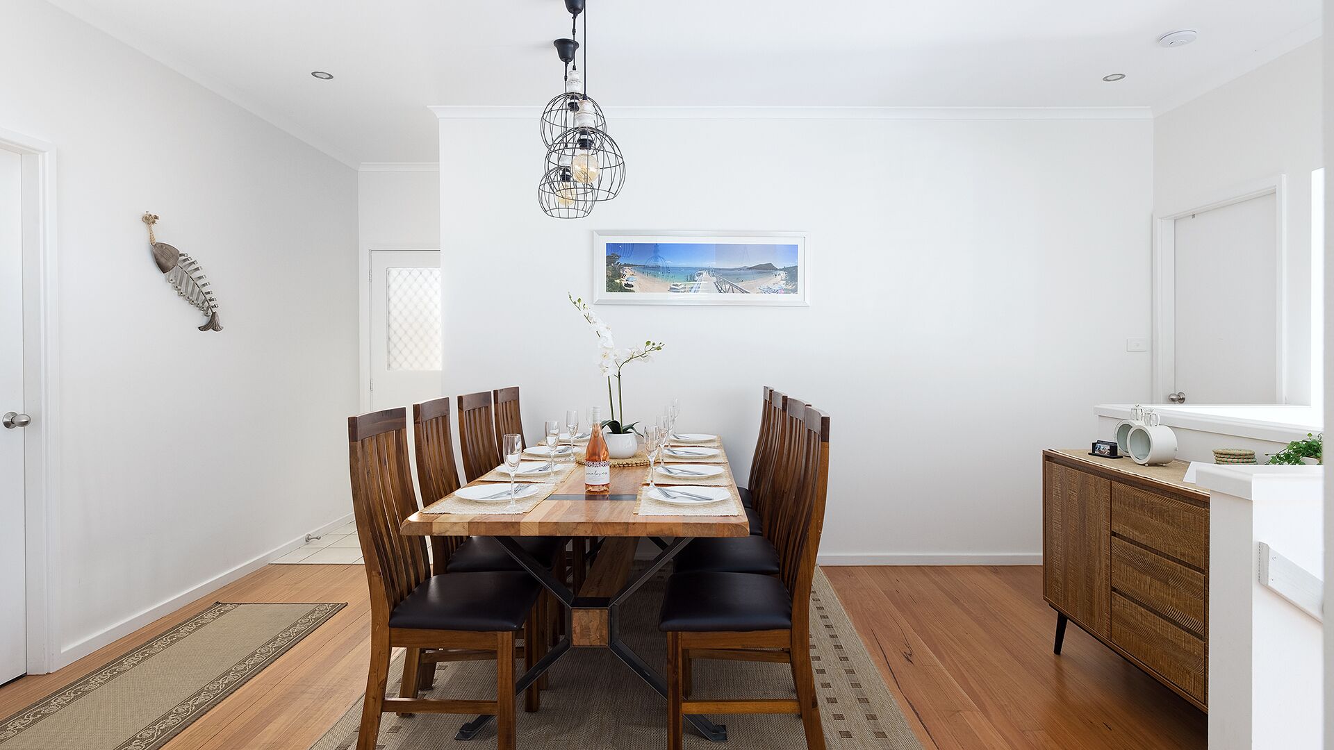 Comedor con una mesa de madera dispuesta para seis personas, rodeada de seis sillas.