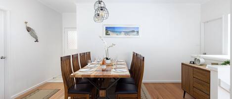 Comedor con una mesa de madera dispuesta para seis personas, rodeada de seis sillas.