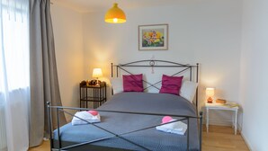 Ein ordentlich eingerichtetes Schlafzimmer mit einem Metallbettgestell, einem Nachttisch mit Lampe und einem Wandbild.