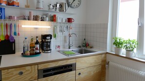 Eine Küche mit Holzausstattung, einem Geschirrspüler, einem Spülbecken und einem Fenster mit Pflanzen.