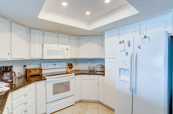 A modern kitchen with white cabinetry, a built-in oven, microwave, and refrigerator.
