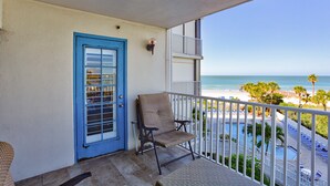 Un balcón con vista a la playa, una puerta azul y una silla.