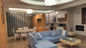 Ein modernes Wohnzimmer mit einer Eckcouch, einem Glastisch und einem Essbereich mit weißem Tisch und Stühlen.
