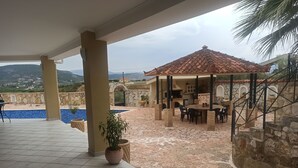 Ein überdachter Außenbereich mit Pool, Esstisch und Stühlen.