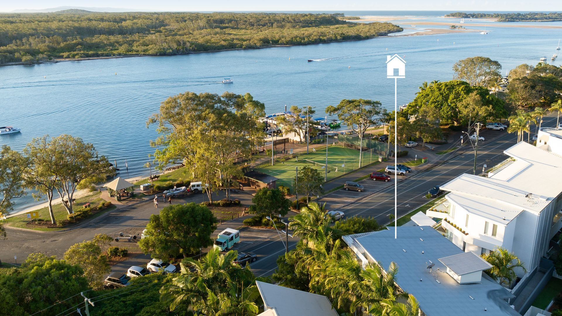 A coastal area with a marina, a tennis court, and a parking lot.