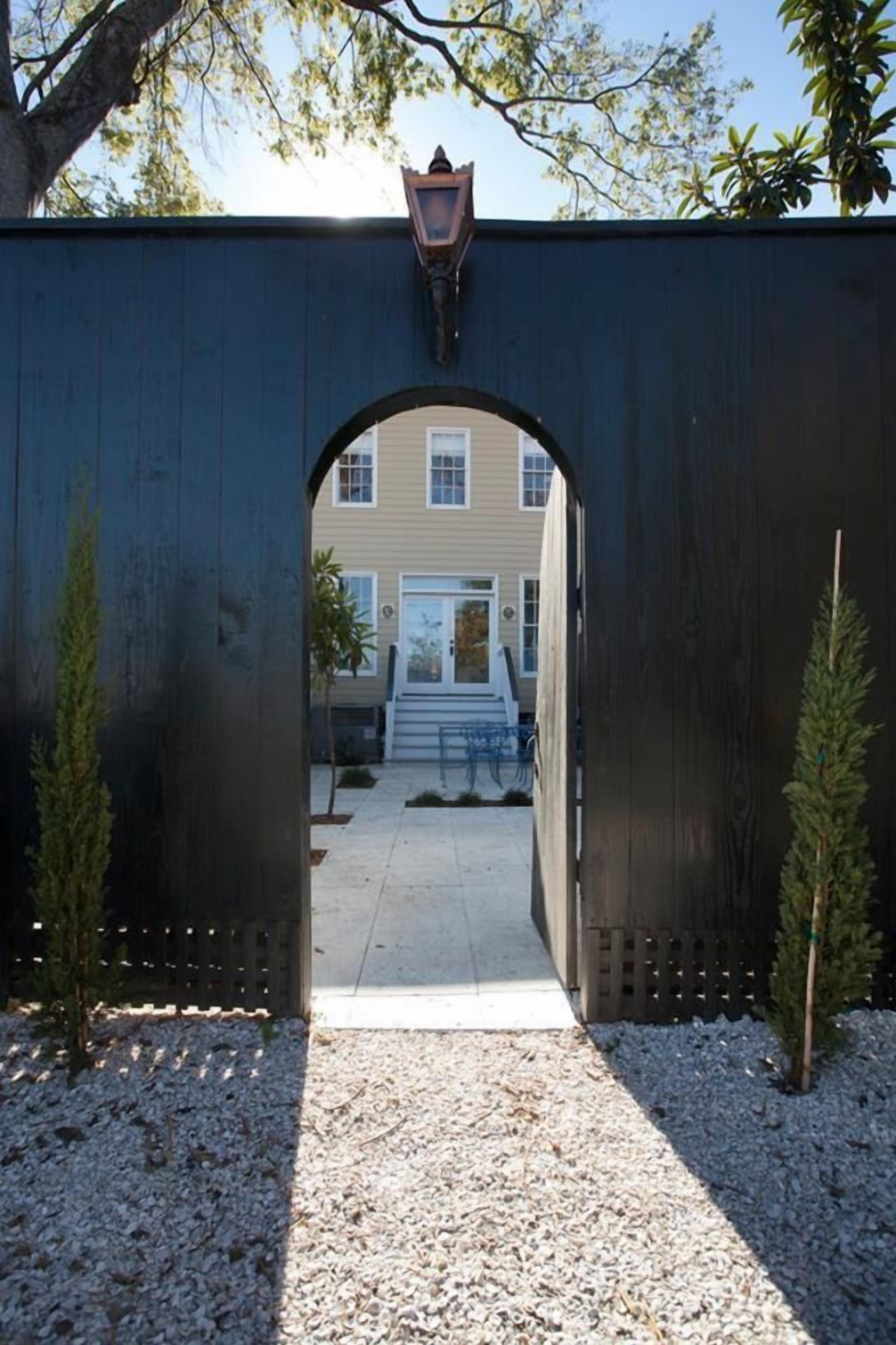 A pathway leading to a building through a dark wooden archway with a lantern above.