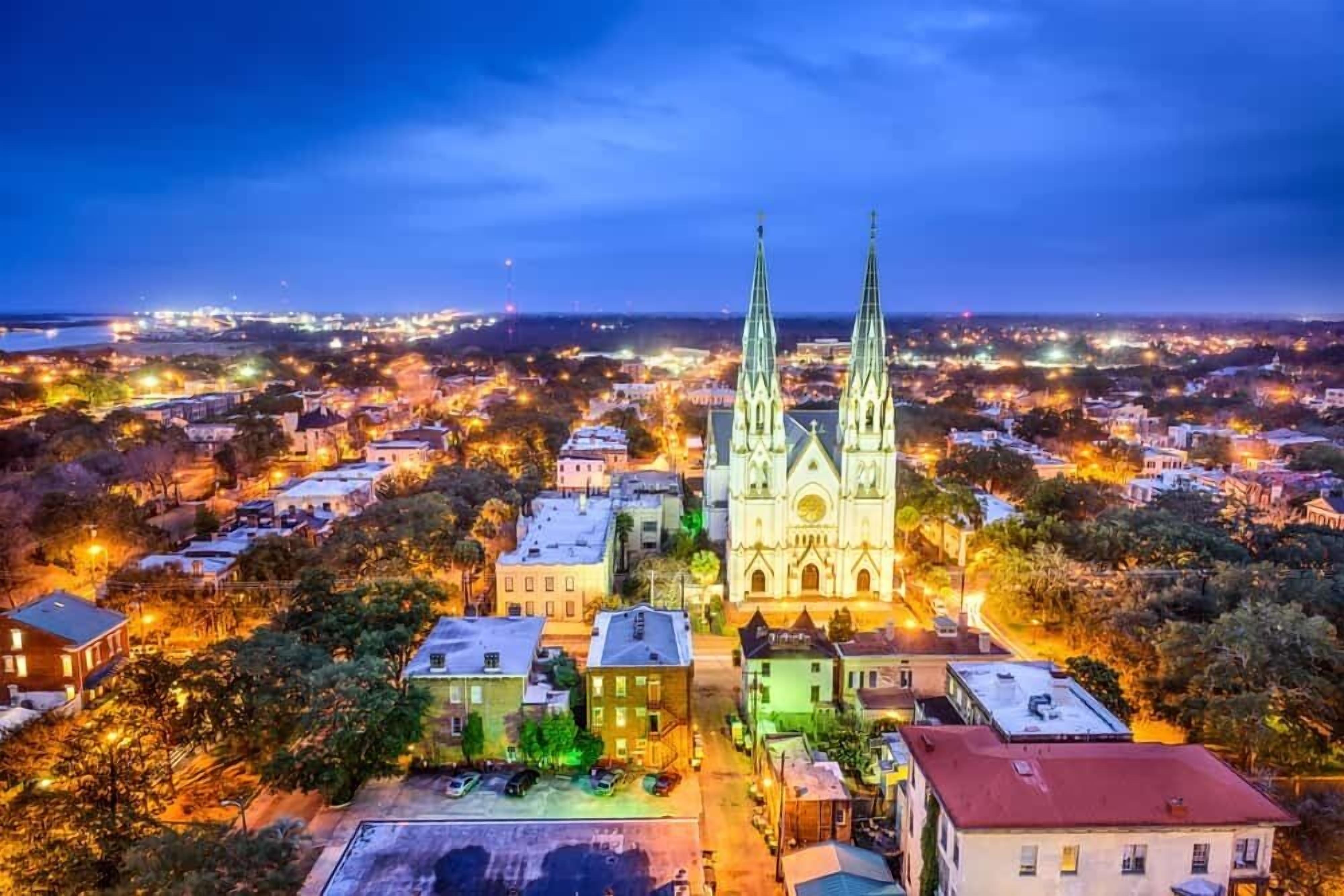 Une cathédrale à deux flèches, entourée d’une vue urbaine au crépuscule.