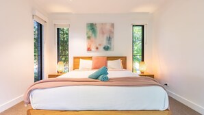 Un dormitorio con una cama grande, dos mesitas de noche con lámparas y un cuadro en la pared.