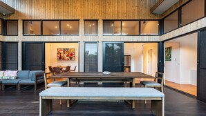 Un comedor amplio con una mesa larga y bancos, ventanas grandes y un diseño interior moderno.