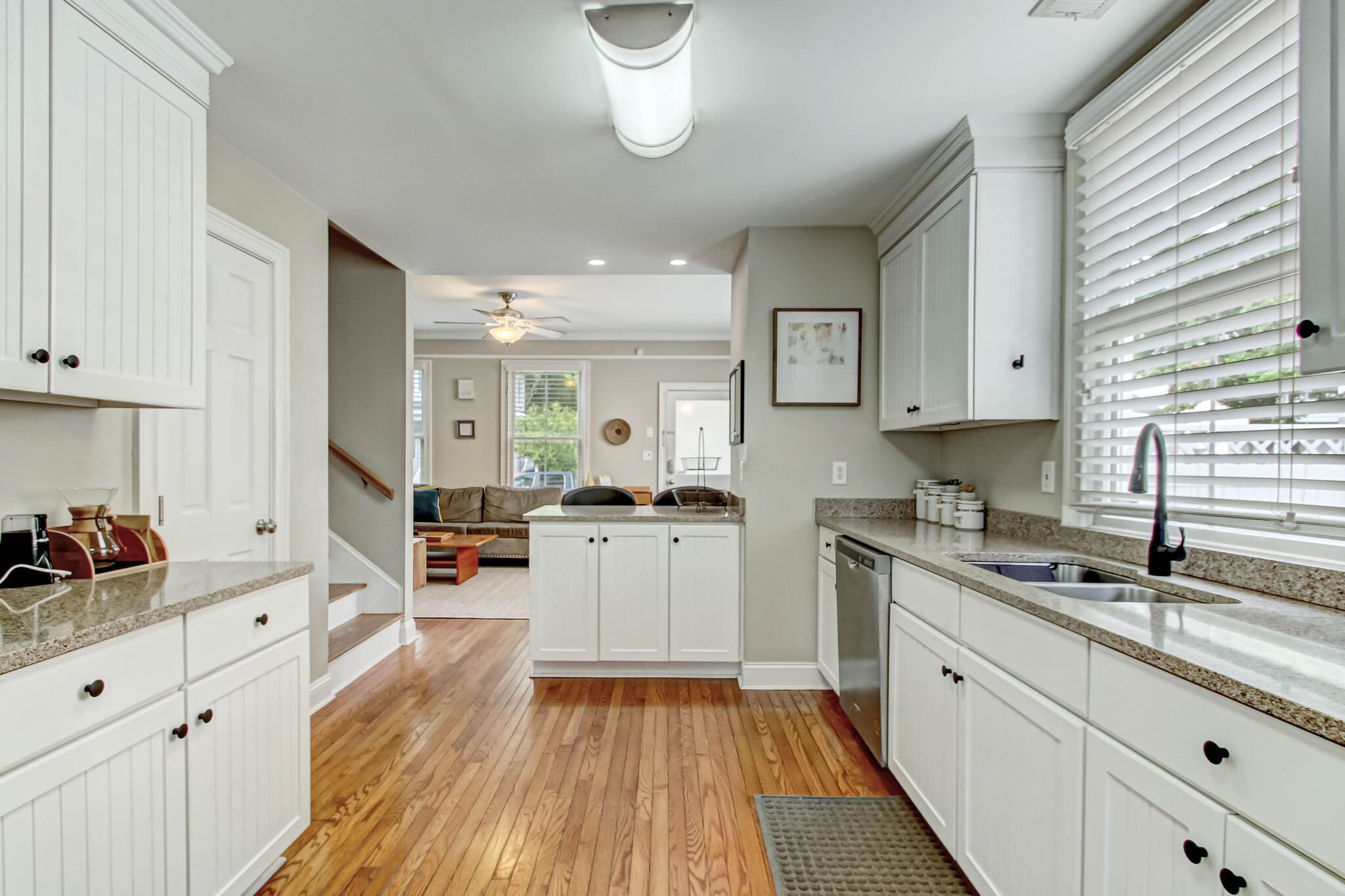 A modern kitchen with white cabinetry, a granite countertop, and a built-in dishwasher.