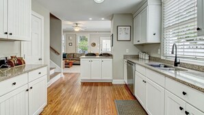A modern kitchen with white cabinetry, a granite countertop, and a built-in dishwasher.