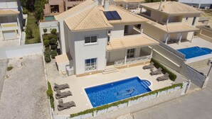 A multi-story residential building with a swimming pool, outdoor seating, and a covered patio area.