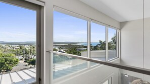 Enjoy breathtaking views of the coast from this apartment's spacious balcony, overlooking a beach and distant mountains.