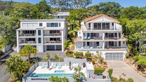 Relax in a serene environment surrounded by lush greenery, with a spacious pool area and multiple balconies for outdoor seating.