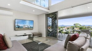 Relax in style with a large flat-screen TV, comfortable seating area, and sliding glass door leading to a balcony with scenic views.