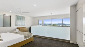 Relax in this serene bedroom with a large bed, dresser, and ceiling fan, offering a stunning view of the surrounding landscape.