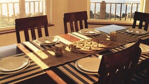 A dining area with a view of a lake and mountains, featuring wooden chairs, a striped tablecloth, and a fish decoration on the wall. - Waterfront only 2 miles from downtown!  Sleeps 8. Amazing Views! (Ketchikan)