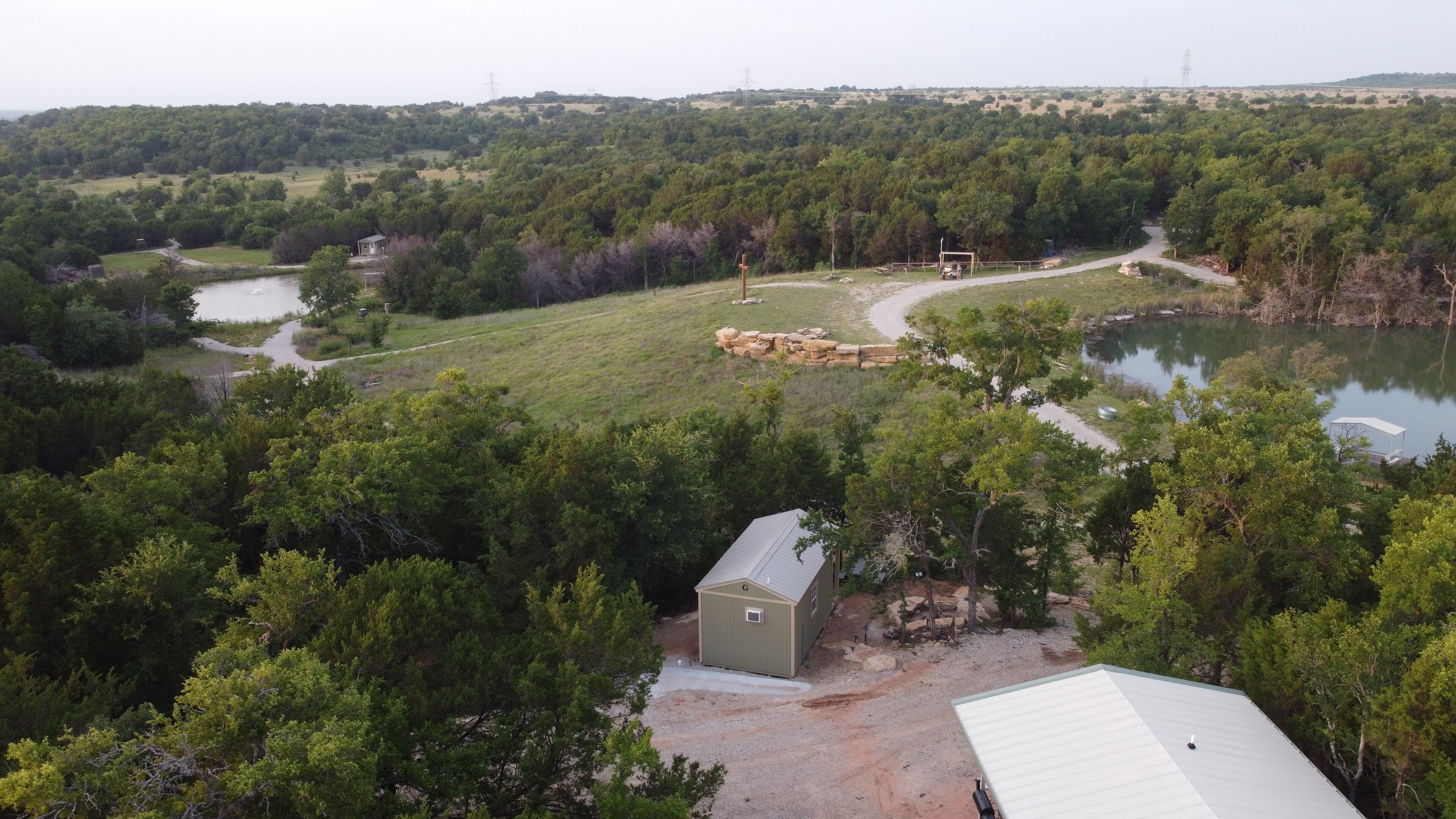 A rural property with a small cabin, a pond, and a dirt path.