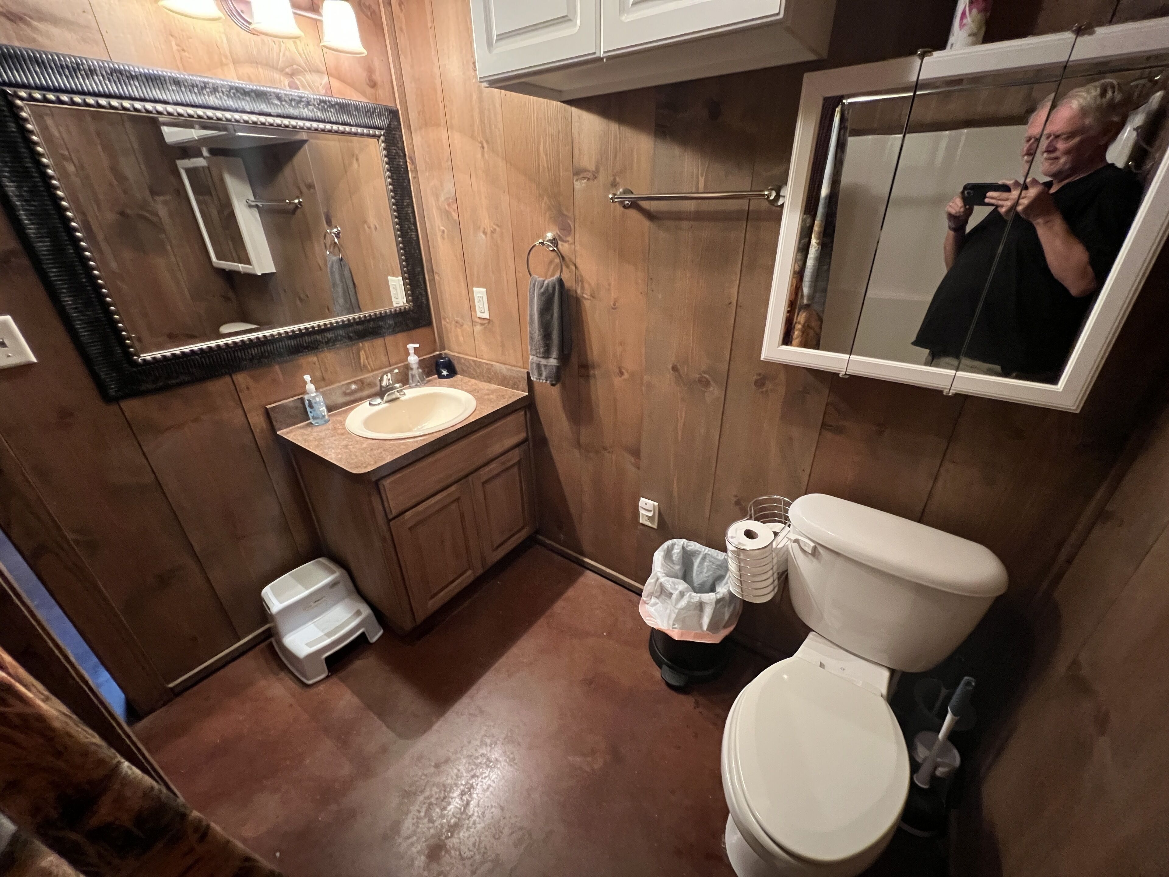Un baño con paneles de madera, un lavabo, un espejo y un inodoro.