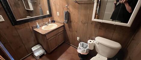 Un baño con paneles de madera, un lavabo, un espejo y un inodoro.