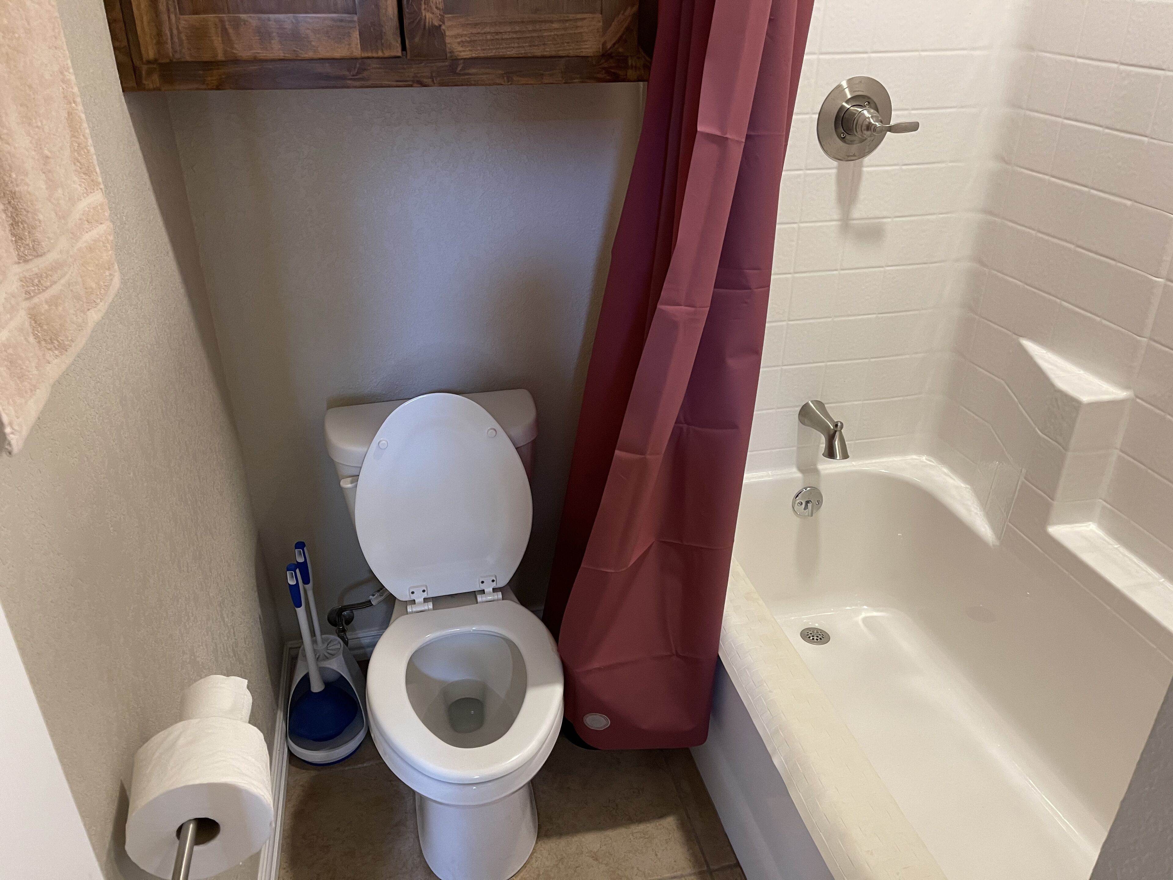 Un baño con inodoro, cortina de ducha, bañera y dispensador de papel higiénico.