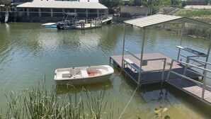 Un quai avec un bateau, un espace abrité et un bâtiment doté d’un toit en pente.