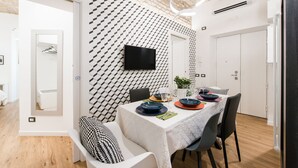 A modern dining area with a geometric patterned wall, a flat-screen TV, and a table set for four. - Charming Trastevere home overlooking a medieval church: suite, 3 baths, WiFi, AC (Roma)