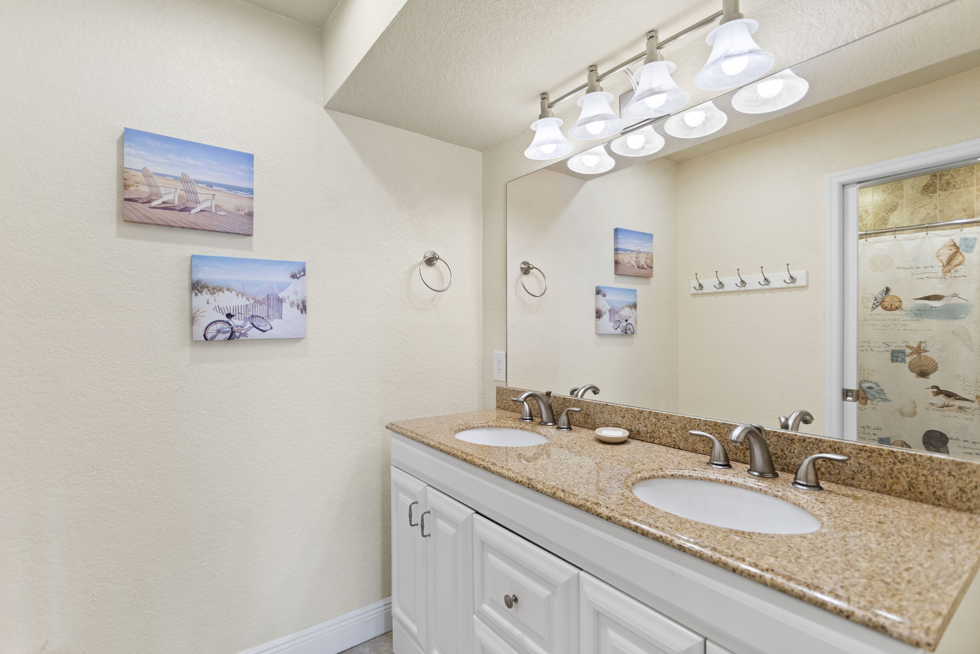 A bathroom with two sinks, a large mirror, and wall-mounted towel rings.