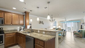 A spacious kitchen with granite countertops, wooden cabinets, and stainless steel appliances.