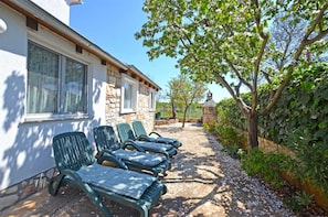 A stone building with a row of green lounge chairs outside.