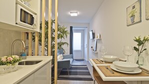 A modern kitchen with a microwave, sink, and a dining area with a table set for two. - OLD TOWN PRÍNCIPE REAL - Apart. modern with patio and direct access to quiet street. (Lisboa)
