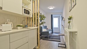A modern kitchen with a microwave, toaster, and potted plants. A blue chair is visible in the background. - OLD TOWN PRÍNCIPE REAL - Apart. modern with patio and direct access to quiet street. (Lisboa)