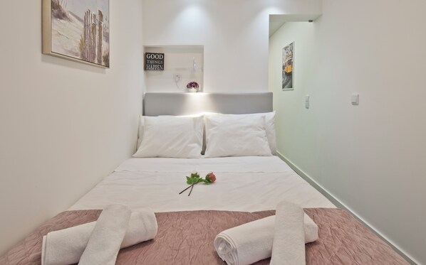 A neatly made bed with white linens, a pink quilt, and two rolled towels. A single rose is placed on the bed. - OLD TOWN PRÍNCIPE REAL - Apart. modern with patio and direct access to quiet street. (Lisboa)