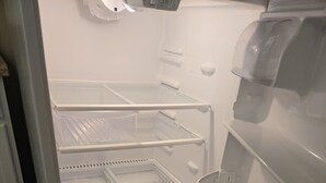 Un refrigerador vacío con varios estantes y dispensador de agua.