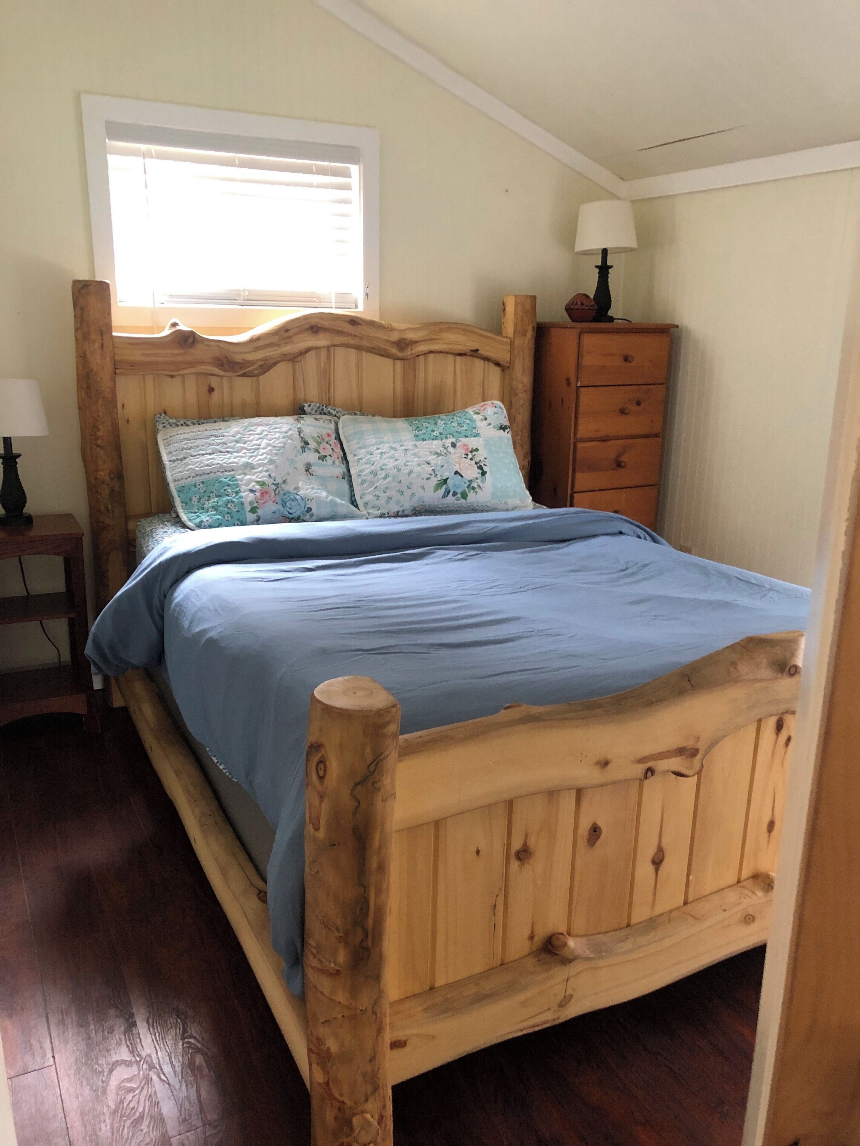 A wooden bed with a headboard, a nightstand with a lamp, and a dresser with drawers.