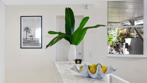 A kitchen with a marble countertop, a white vase with a plant, and a framed picture on the wall.