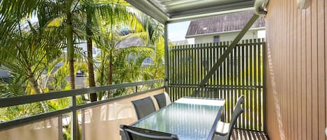 An outdoor patio with a table and chairs, surrounded by a wooden fence and lush greenery.
