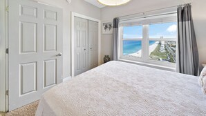 Une chambre avec un grand lit, une vue sur la plage et un luminaire au plafond.
