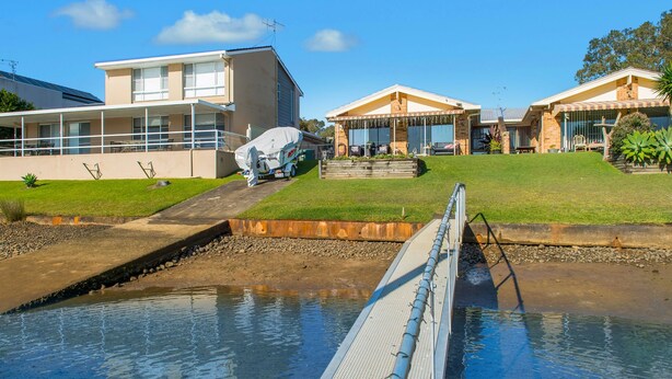 A residential area with a swimming pool, a covered boat, and houses with a sloped roof design. - 29A Ballina Crescent, Port Macquarie (Port Macquarie)