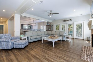 Un salon spacieux avec un canapé d’angle, une table basse et un ventilateur de plafond.