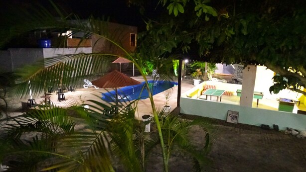 A nighttime view of an outdoor area with a pool, seating, and a table tennis table. - Pousada Dom Hotel (Porto Seguro)