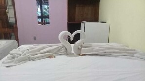A bed with a heart-shaped towel arrangement. - Pousada Dom Hotel (Porto Seguro)
