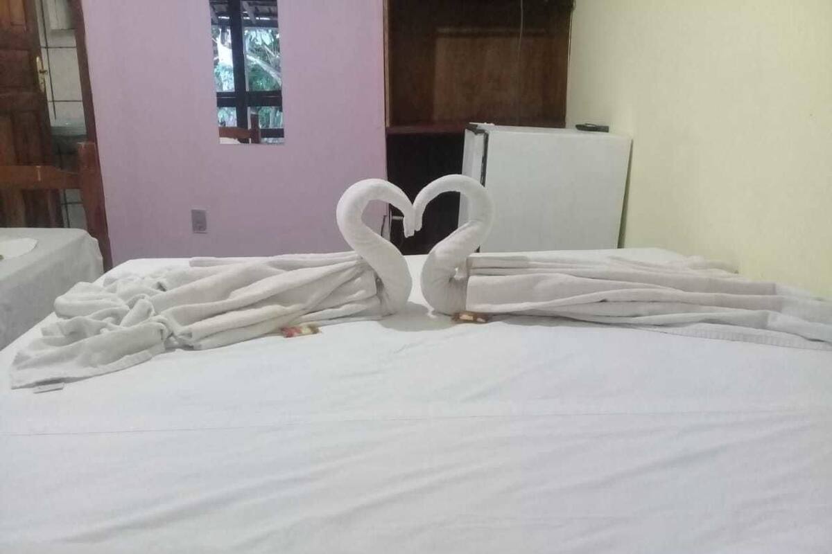 A bed with a heart-shaped towel arrangement.
