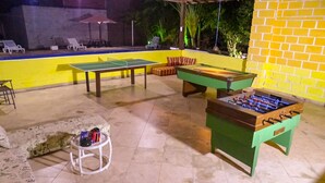 An outdoor recreational area with a foosball table, a ping pong table, and a pool table. - Pousada Dom Hotel (Porto Seguro)
