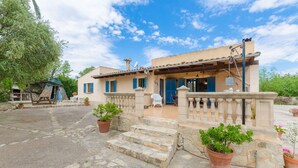 A two-story building with a stone staircase leading to the entrance, surrounded by potted plants and a clear blue sky. - Villa with private pool near Manacor,  Villa con piscina privada en Manacor, YourHouse Garballons (Manacor)