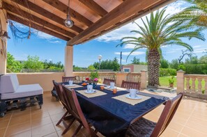 An outdoor patio with a table set for dining, a lounge chair, and a palm tree. - Villa with private pool near Manacor,  Villa con piscina privada en Manacor, YourHouse Garballons (Manacor)
