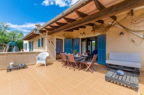 A covered outdoor patio with a table and chairs, a white sofa, and a decorative bowl. - Villa with private pool near Manacor,  Villa con piscina privada en Manacor, YourHouse Garballons (Manacor)