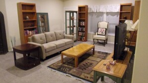 A living room with a sofa, coffee table, TV, and bookshelves. - $89/night for 2 people, plus $20/night for each additional person (Pahrump)