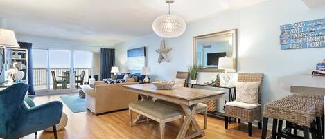 A spacious living area with a wooden dining table, blue armchairs, a bench, and a large starfish decoration.