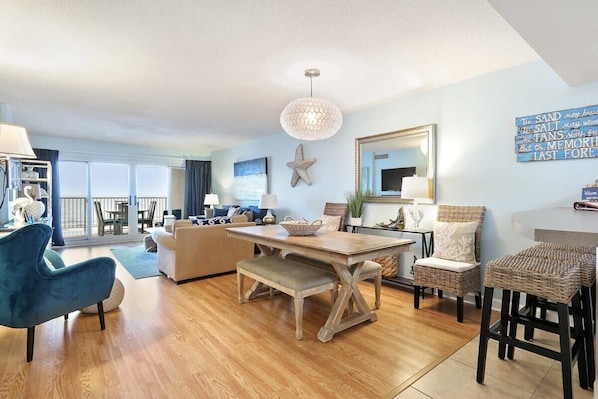 A spacious living area with a wooden dining table, blue armchairs, a bench, and a large starfish decoration.